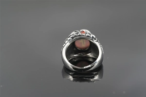 Macro detail of gothic snake ring with orange eye stone and engraved steel patterns