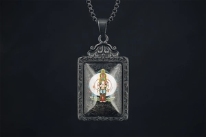 Macro detail of Buddhist Thangka pendant with ornate relief patterns and box chain