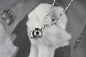 Detailed close-up of a vintage 3D mini camera pendant necklace with intricate lens textures