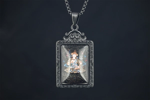 Detailed macro view of retro Buddhist pendant with intricate relief carvings and colorful Thangka icon