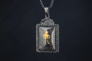Close-up of vintage Thangka Buddha pendant featuring relief patterns and metallic frame