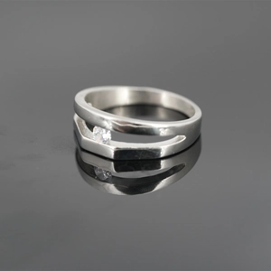 Minimalist silver double-layer ring with sparkling center stone on reflective background