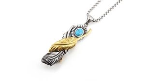 Detail of vintage feather pendant with blue turquoise inlay on silver and gold metal
