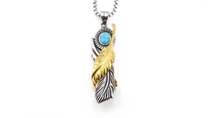 Detailed close-up of retro punk turquoise feather pendant with silver and gold sun disk