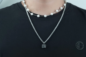 Close-up of a double-layer men's pearl and steel chain necklace with a Paris cube pendant