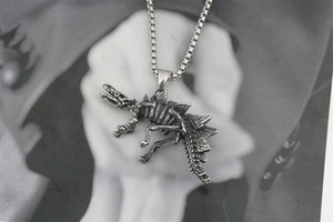 Macro shot of retro stainless steel stegosaurus dinosaur skeleton pendant with box chain