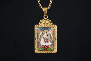 Detail of a gold Buddhist Thangka pendant featuring intricate hollowed floral carvings