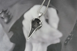 Détail d'un pendentif tête de corbeau gothique en acier inoxydable sur fond sombre