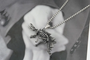 Macro shot of retro dinosaur skeleton pendant with vintage silver finish and box chain