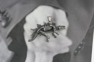 Macro shot of retro silver stegosaurus skeleton pendant with vintage steel texture