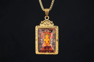 Close-up of a Tibetan Thangka Buddhist Buddha pendant with gold relief frame and box chain