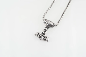 Dettaglio del ciondolo martello di Thor Mjölnir vintage con incisioni nordiche su catena box