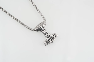Dettaglio del ciondolo martello di Thor Mjölnir in acciaio argento con rune nordiche