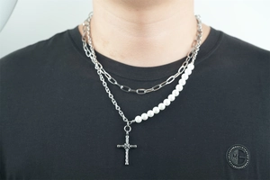 Dettaglio della collana a strati in acciaio al titanio con croce e perle su un modello