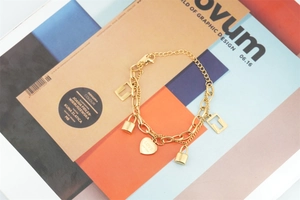 Detailed macro view of a layered gold heart and key lock charm bracelet for women