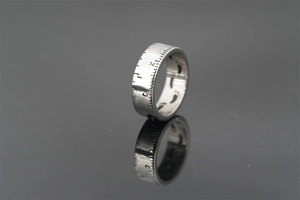 Detail shot of silver titanium ring featuring ruler scale and inner footprint patterns