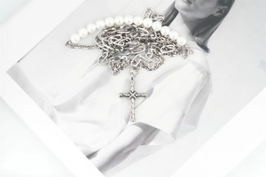 Dettaglio della collana con croce con perle bianche e catene in acciaio inossidabile