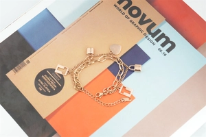 Close-up of rose gold double-layer steel bracelet with LOVE heart and lock charms
