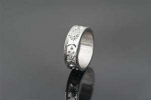 Détail d'une bague argentée avec relief soleil et lune et motif céleste au fini mat