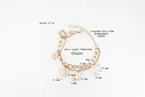 Detail view of rose gold layered bracelet with heart and lock charms with dimensions