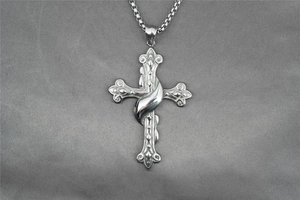 Gros plan du pendentif croix en acier inoxydable argenté avec texture florale et chaîne box