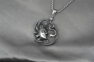 Dettaglio macro del ciondolo testa di Medusa in argento vintage con texture di serpente su seta