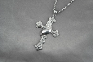 Gros plan d'un pendentif croix argenté avec un design profilé sur une chaîne box