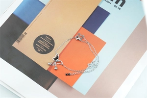 Detail view of silver butterfly bracelet with star charm on a magazine background
