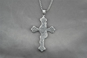 Détail d'un grand pendentif croix en acier inoxydable avec relief sur une chaîne box