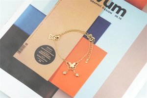 Detail of gold butterfly bracelet with star charms and zircons on design magazine