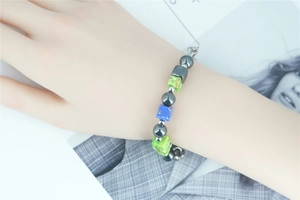 Close-up of a beaded bracelet with grey, green, and blue marble cubes on a wrist