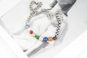 Détails des perles planètes et des maillons asymétriques sur un collier design chic