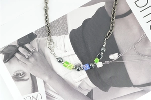 Detail of silver heavy chain necklace featuring colorful beads and toggle clasp design
