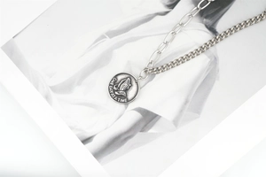 Détail d'un collier vintage avec pendentif mains en prière et gravure de citation inspirante