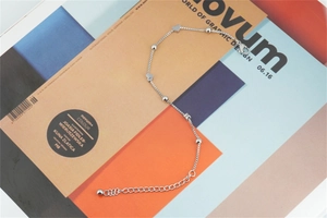 Detail of silver box chain bracelet with 3D heart charms and polished beads on a magazine
