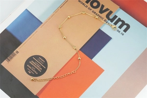 Detail view of a gold-plated stainless steel bead bracelet with heart charms and lobster clasp