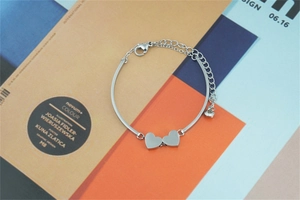 Polished silver heart-shaped bracelet featuring two linked hearts on sleek metal bands