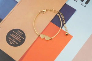 Close-up of golden double heart bracelet with lobster clasp and adjustable link chain