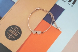 Close-up of rose gold heart bracelet with lobster clasp on artistic background