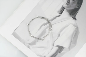 Détail d'un bracelet double couche en acier inoxydable argenté avec petits cœurs et perles