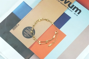 Close-up of double-layer gold star anklet with delicate beads on a colorful magazine