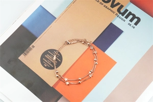 Close-up of rose gold double-layer star bracelet with snake chain on magazine background