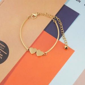 Chic gold-plated double heart charm bracelet with adjustable chain on fashion magazine