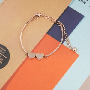 Minimalist double heart rose gold bracelet with adjustable chain on a stylish magazine background
