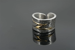 Macro detail of industrial wide ring with hammered texture and golden lightning bolt motif