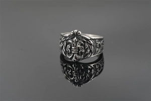 Macro shot of vintage titanium steel punk ring with embossed fleur-de-lis and gothic patterns