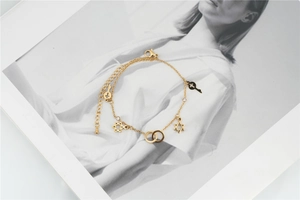 Macro detail of a gold chain bracelet featuring hexagram star and cross coin pendants