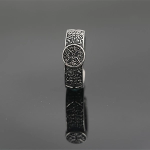 Vintage titanium steel ring with hammered texture and cross emblem on mirror background