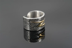 Detail view of vintage wide ring with lava texture and golden lightning bolt motif