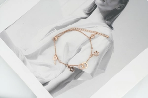 Detail view of rose gold anklet with star, key, and cross charms on fashion background